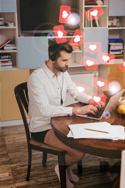 Selective focus of freelancer in shirt and panties using headset and laptop near papers on table at home, likes illustration