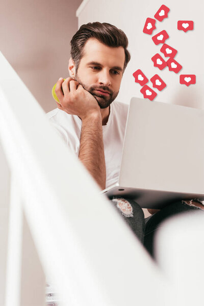 Selective focus of teleworker holding apple and using laptop on staircase, likes illustration