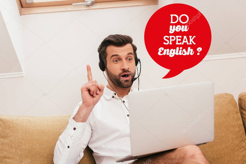 Selective focus of excited freelancer in headset showing idea gesture during video chat on laptop at home, do you speak English illustration