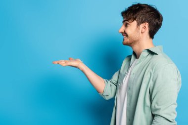 Mavi kollu mutlu genç adamın yan görüntüsü.