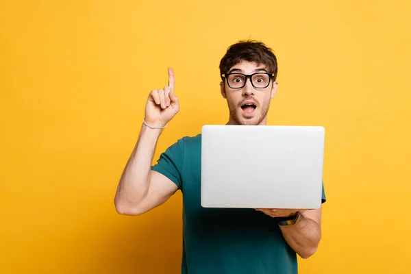 Aufgeregter Junger Mann Zeigt Ideengeste Während Laptop Auf Gelb Hält — Stockfoto