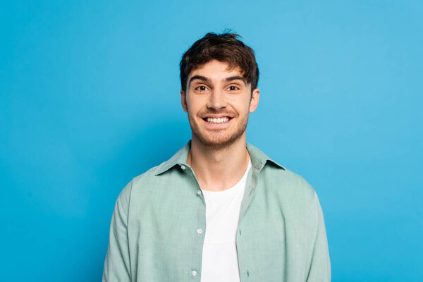 cheerful young man smiling at camera on blue