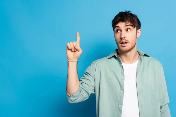 Réfléchi Jeune Homme Pointant Doigt Tout Regardant Loin Sur Bleu — Photo