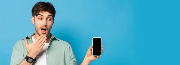 Горизонтальное Изображение Шокированного Молодого Человека Показывающего Смартфон Чистым Экраном Синем — стоковое фото