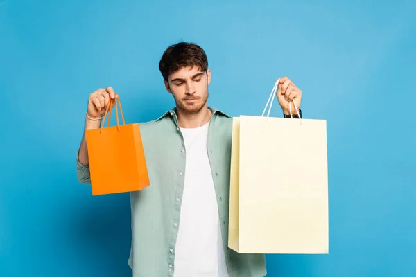 Pensativo Joven Sosteniendo Bolsas Compras Azul —  Fotos de Stock