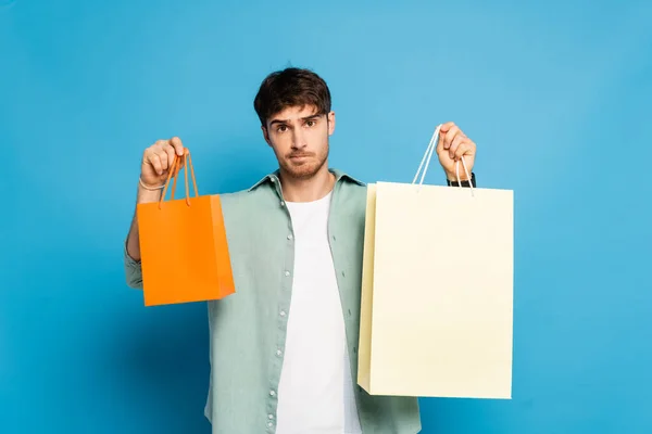 Pensativo Joven Mostrando Bolsas Compras Azul —  Fotos de Stock