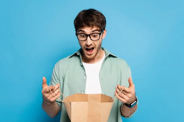 Jovem Surpreso Olhando Para Saco Compras Azul — Fotografia de Stock