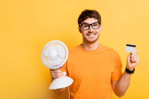 Happy Man Eyeglasses Holding Credit Card Electric Fan Yellow — Stock Photo, Image