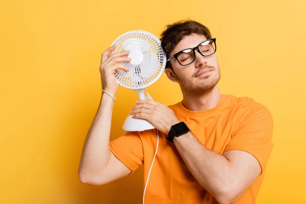 Álmodozó Férfi Csukott Szemmel Szemüvegben Tartja Elektromos Ventilátor Sárga — Stock Fotó