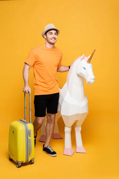 Lächelnder Reisender Mit Hut Einhorn Und Koffer Auf Gelb — Stockfoto