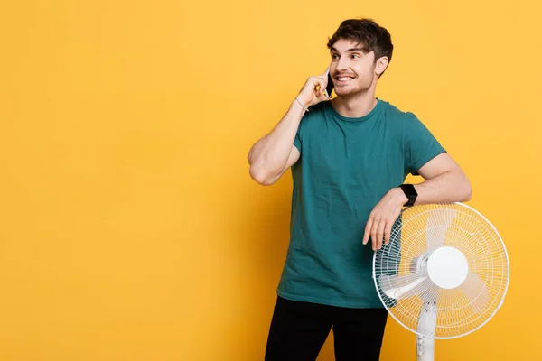 Sorrindo Homem Falando Celular Enquanto Estava Perto Ventilador Elétrico Amarelo — Fotografia de Stock