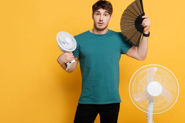 Young Man Suffering Heat Two Electric Fans Hand Fan Yellow — Stock Photo, Image
