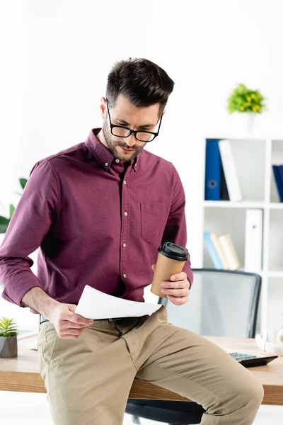 Junger Seriöser Geschäftsmann Sitzt Schreibtisch Liest Dokument Und Hält Kaffee — Stockfoto