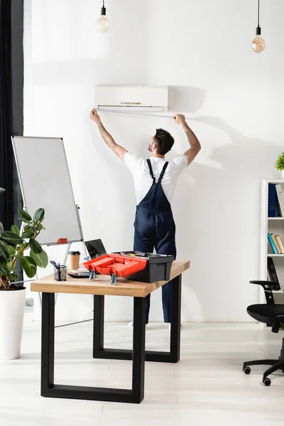 Achteraanzicht Van Reparateur Meten Airconditioner Muur Kantoor — Stockfoto