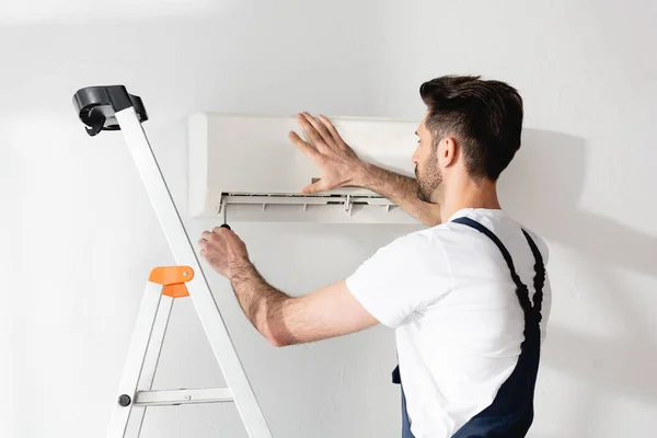 Young Repairman Standing Stepladder Fixing Air Conditioner — Stock Photo, Image