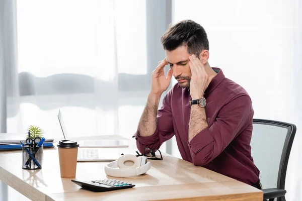 tired businessman touching head while suffering from migraine with closed eyes