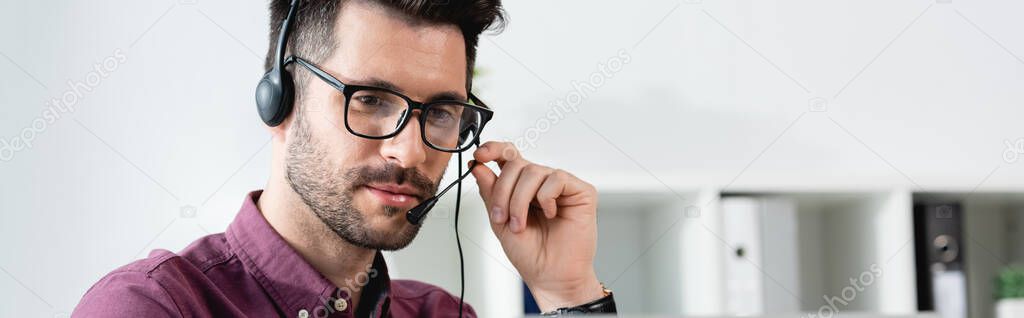 horizontal image of young businessman in headset having online call