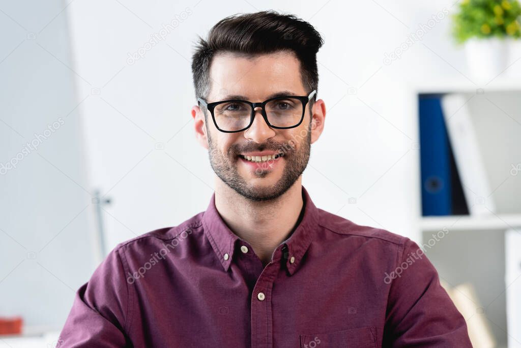 happy, handsome businessman in eyeglasses smiling while looking at camera