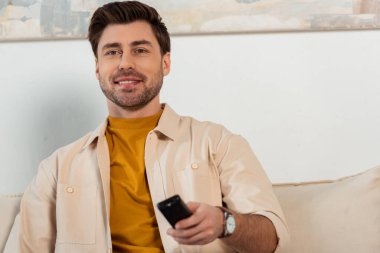 Evde uzaktan kumandalı yakışıklı bir adamın seçici odak noktası 