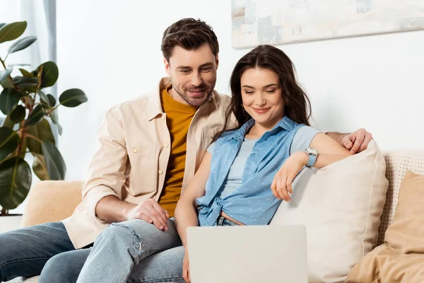 Foco Seletivo Homem Bonito Sentado Perto Namorada Sorridente Laptop Sofá — Fotografia de Stock