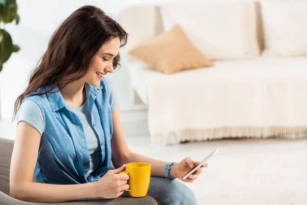 Mujer Sonriente Sosteniendo Una Taza Café Usando Teléfono Inteligente Casa — Foto de Stock