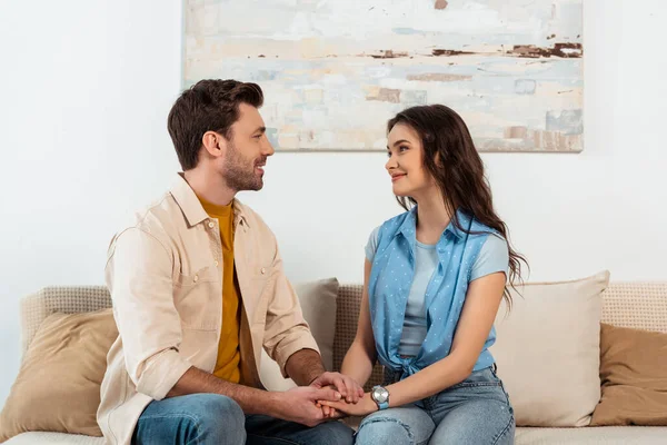 Pareja Sonriente Mirándose Tomándose Mano Sofá Casa — Foto de Stock