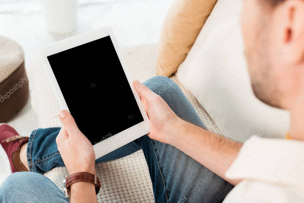 Selective focus of man holding digital tablet with blank screen on sofa 