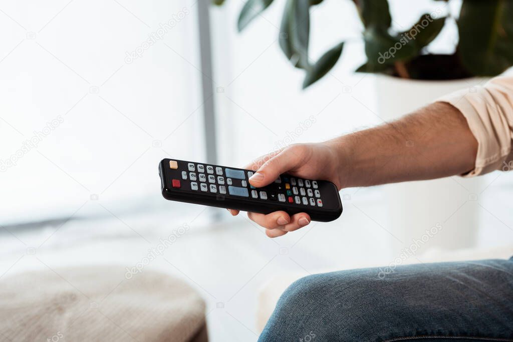 Cropped view of man holding remote controller at home