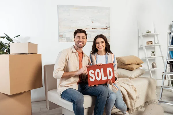 Cheerful Couple Looking Camera While Holding Nameplate Sold Lettering Carton — Stock Photo, Image