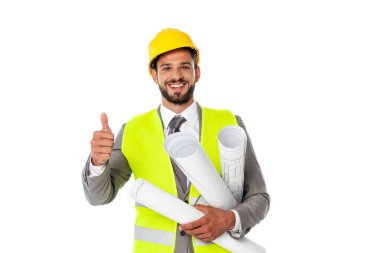 Handsome engineer showing thumb up while holding blueprints and smiling at camera isolated on white clipart