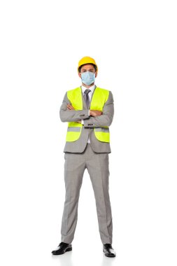 Kollarını kavuşturup beyaz arka plandaki kameraya bakan tıbbi maskeli bir mühendis.