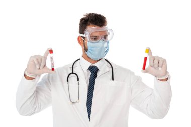 Güvenlik maskesi ve gözlüklü doktor beyaz üzerinde izole edilmiş kan örneklerinden oluşan test tüpleri tutuyor.