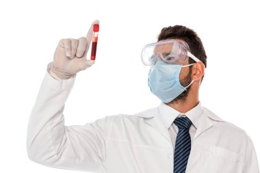 Tıbbi maskeli ve koruyucu gözlüklü bir doktor beyaz üzerinde kan örneği olan test tüpü tutuyor.