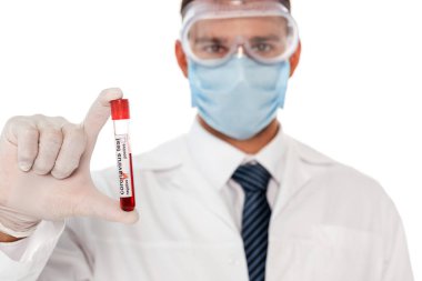 Koruyucu maskeli ve gözlüklü doktorun seçici odak noktası beyaz harflerle izole edilmiş kan örneği ve koronavirüs içeren test tüpü tutması.