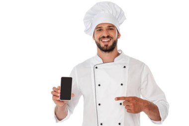 Yakışıklı sakallı şef beyaz telefondan izole edilmiş akıllı telefonu işaret ediyor.