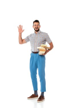 Smiling nerd holding books and waving hand at camera on white background clipart