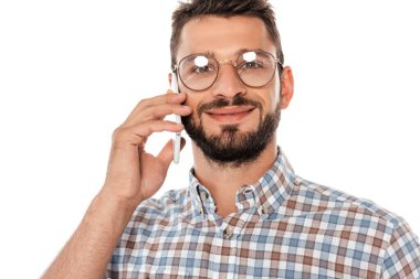 Smiling near in eyeglasses looking at camera while talking on smartphone isolated on white clipart