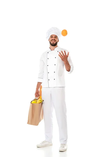 Usmívající Kuchař Uniformě Házení Oranžové Držení Nákupní Tašky Jídlem Bílém — Stock fotografie
