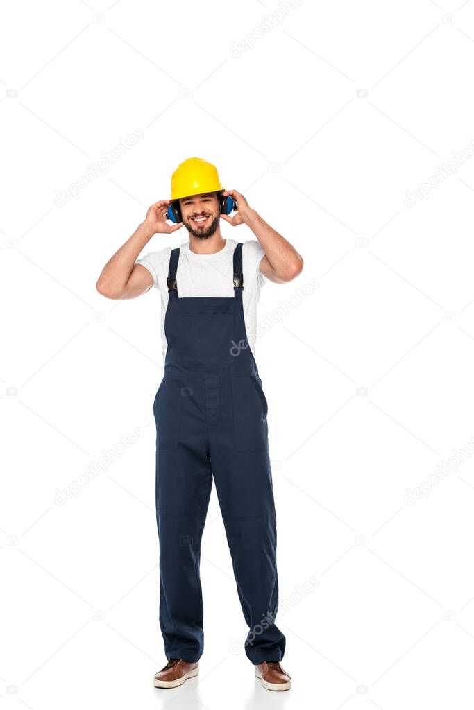 Smiling workman in hardhat and ear defenders looking at camera on white background