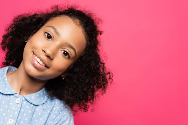 Gülümseyen kıvırcık saçlı Afrikalı Amerikalı çocuk pembe kameraya bakıyor.