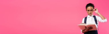 Gözlüklü Afrikalı Amerikalı kız. Pembe, panoramik bir karede izole edilmiş kitap okuyor.