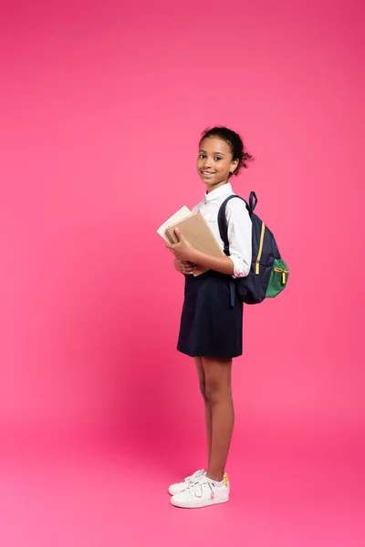 Вид Сбоку Улыбающейся Африканской Школьницы Рюкзаком Книгами Розовом Фоне — стоковое фото