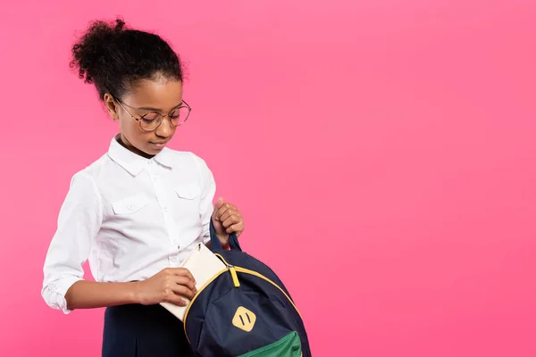African American Schoolgirl Glasses Putting Book Backpack Isolated Pink — Stock Photo, Image