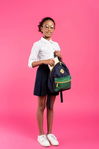 Smiling African American Schoolgirl Glasses Putting Book Backpack Pink — Stock Photo, Image