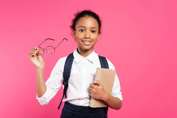 Leende Afrikansk Amerikansk Skolflicka Med Bok Och Glasögon Isolerade Rosa — Stockfoto