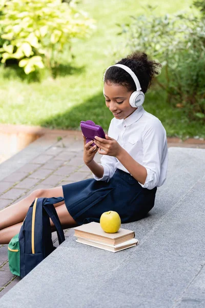 Smiling African American Schoolgirl Listening Music Headphones Backpack Books Lunch — Stock Photo, Image