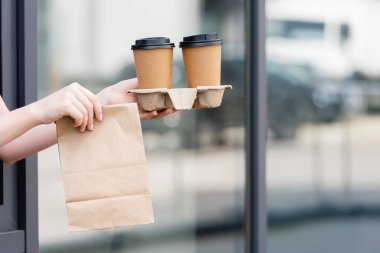 Garsonun elinde kese kâğıdı ve kahve tutarken kentsel caddedeki kafenin yakınına gittiği görüntüler. 