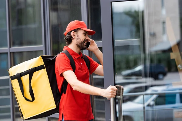 Smiling Courier Thermo Backpack Talking Smartphone While Opening Door Building — Stock Photo, Image