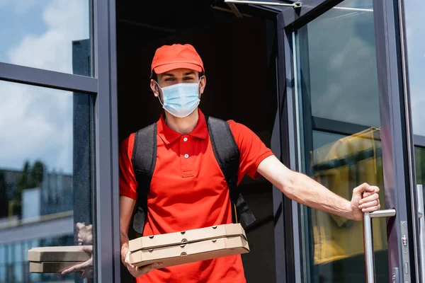 Entrega Homem Máscara Médica Uniforme Segurando Caixas Pizza Perto Porta — Fotografia de Stock