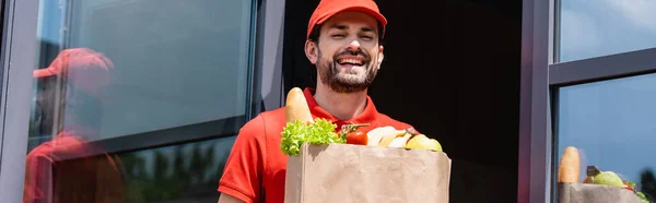 Panoramic Shot Positive Delivery Man Holding Shopping Bag Grocery Urban — Stock Photo, Image